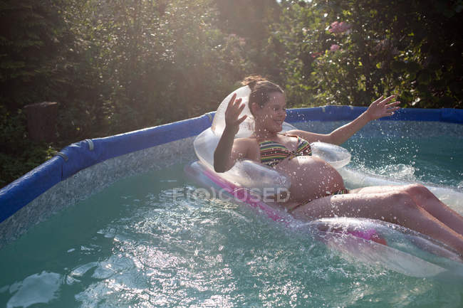 Donna incinta galleggiante in piscina — Foto stock