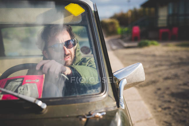 Homem no carro do vintage estacionado olhando através do espelho da asa — Fotografia de Stock