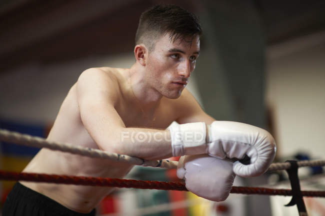 Boxer leaning on ropes of boxing ring — Stock Photo