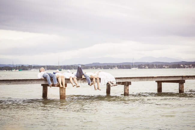 Gruppe von Freunden liegt in einer Reihe auf Seebrücke — Stockfoto
