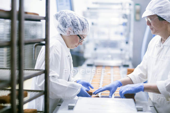 Заводські робітники на лінії виробництва продуктів харчування — стокове фото