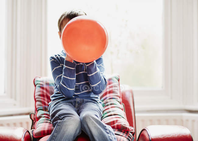 Jovem menino segurando balão na frente da cara — Fotografia de Stock