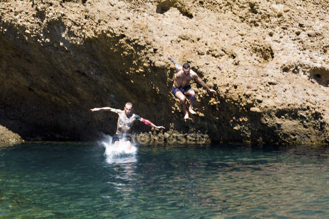 Двоє молодих чоловіків стрибають в море з гірських порід, Марсель, Франція — стокове фото