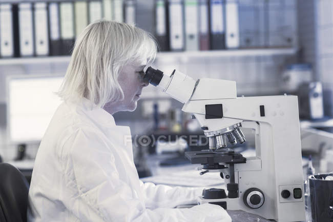 Científico usando microscopio en laboratorio - foto de stock