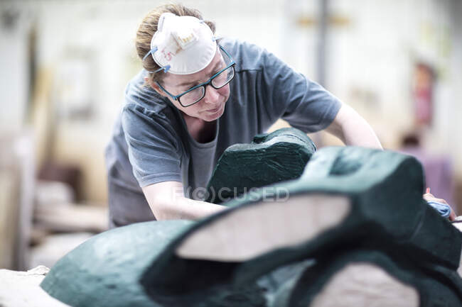 Trabajadora de fundición acabando escultura de bronce en fundición de bronce - foto de stock