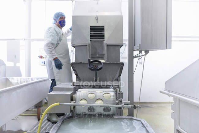 Mozzarella-forming machine operated by worker in cheese factory — Stock Photo