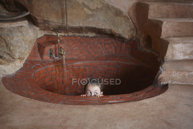 Девушка заглядывает в деревенскую ванну на полу — стоковое фото