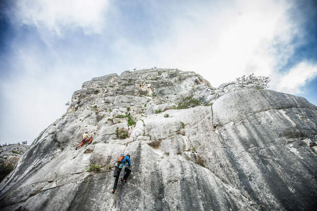 Low angle rear view of rock climber climbing up mountainside, Ogliastra, Sardinia, Italy — Stock Photo