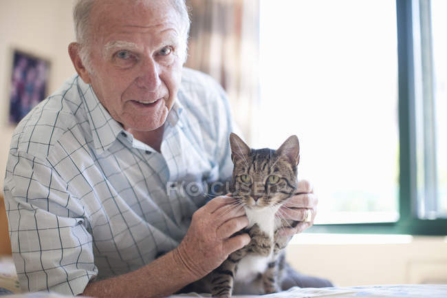 Porträt eines älteren Mannes, der Hauskatze streichelt — Stockfoto