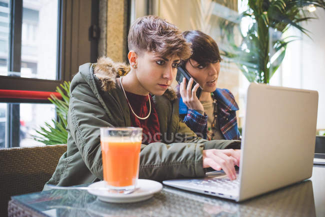 Две сестры в кафе, с помощью ноутбука — стоковое фото