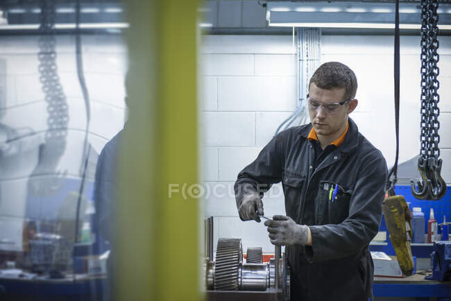 Apprentice engineer assembling industrial gearbox in factory — Stock Photo