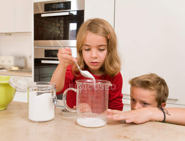 Menina e menino medindo açúcar — Fotografia de Stock