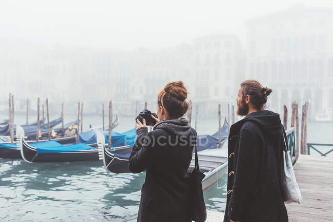 Paar fotografiert Gondeln auf nebligem Kanal, Venedig, Italien — Stockfoto