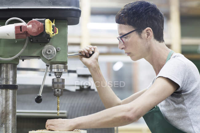 Женщина в мастерской с помощью буровой техники — стоковое фото