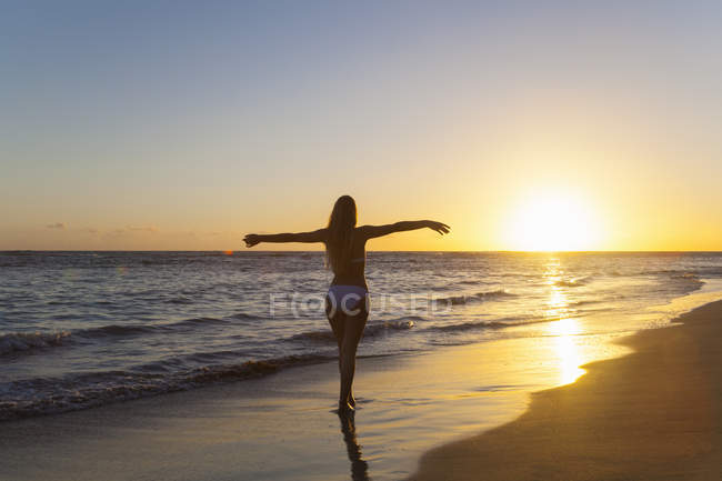 Silhouetted young woman with arms open on beach at sunset, Dominican Republic, The Caribbean — Stock Photo