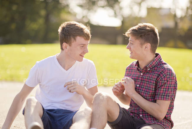 Deux jeunes amis masculins bavardant dans le parc — Photo de stock