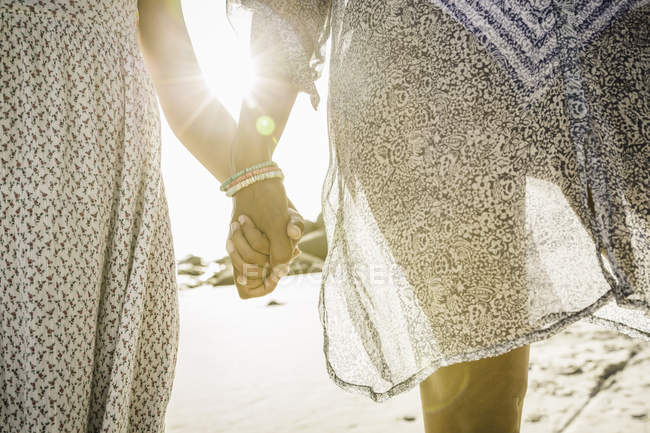 Mère et fille tenant la main sur la plage — Photo de stock