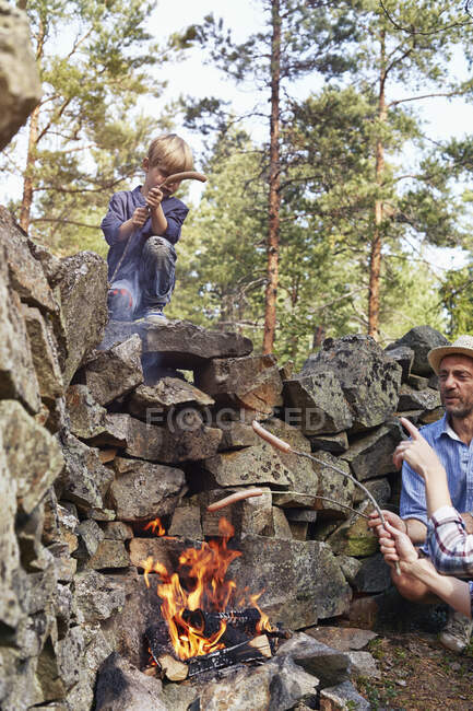 Family cooking sausages over fire — Stock Photo