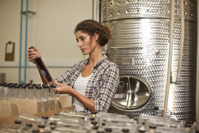 Donna che guarda la bottiglia in distilleria — Foto stock