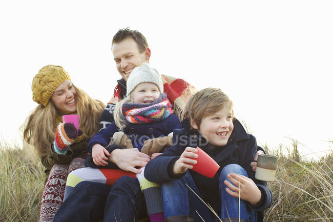 Sonriente pareja adulta con dos hijos en la costa - foto de stock