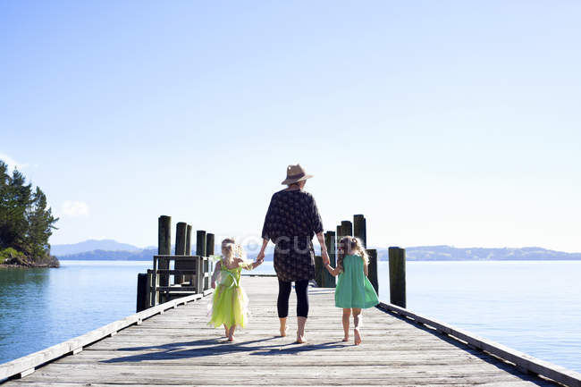 Взрослая женщина и дочери, прогуливающиеся по пирсу, Новая Зеландия — стоковое фото