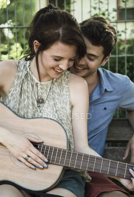 Casal jovem serenata na guitarra acústica no parque — Fotografia de Stock