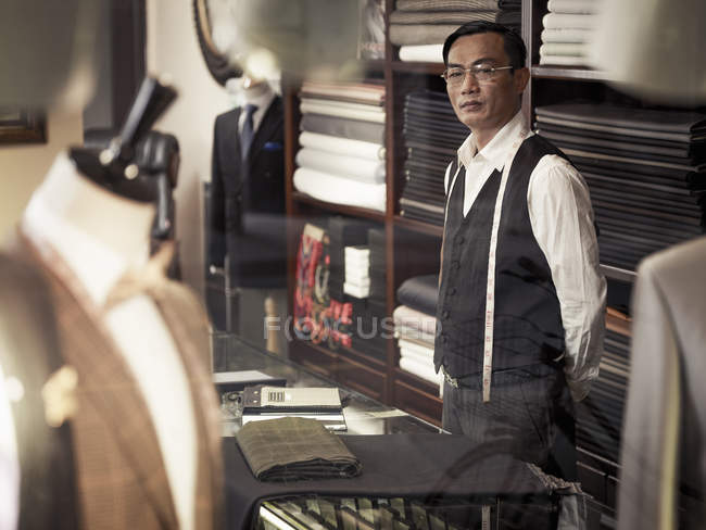 Tailor standing behind counter in tailors shop — Stock Photo