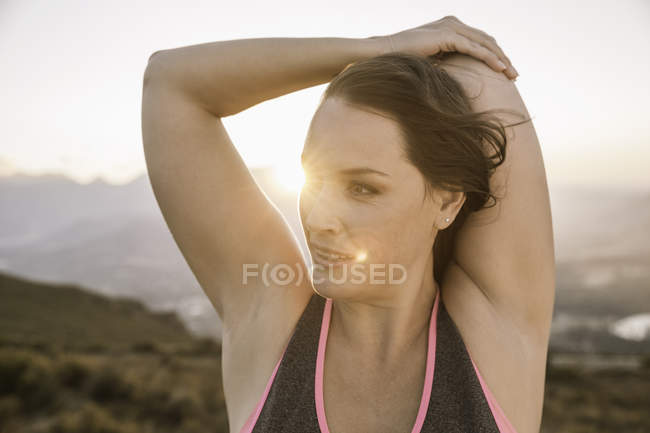 Plus size woman hands behind head stretching as sunrise, looking away — Stock Photo
