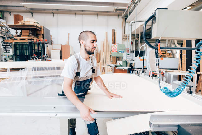 Молодой плотник за работой в мастерской — стоковое фото