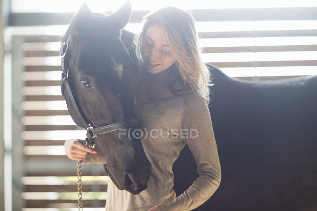 Нежный портрет молодой женщины с черной лошадью — стоковое фото