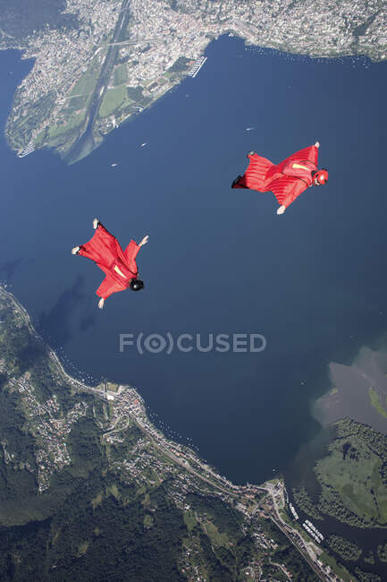 Dos pilotos de paracaidismo de traje de ala entrenando y volando juntos sobre el lago, Locarno, Tessin, Suiza - foto de stock