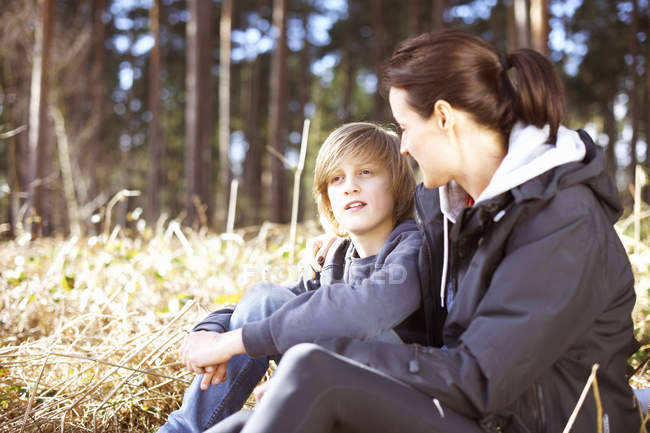 Mature woman taking a break with her son in a forest — Stock Photo