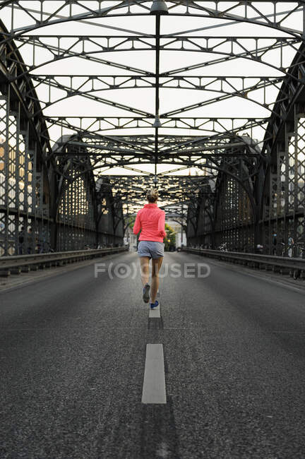 Joven corredora cruzando puente - foto de stock