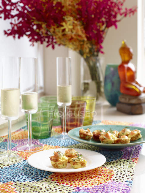 Trout and chive frittatas with champagne flutes of sparkling champagne — Stock Photo