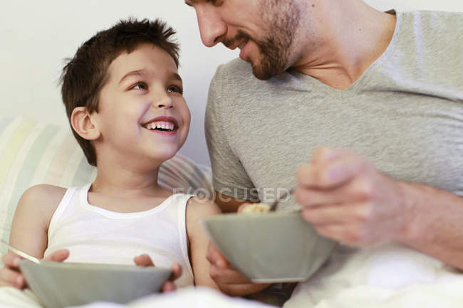 Pai e filho pequeno tomando café da manhã na cama — Fotografia de Stock