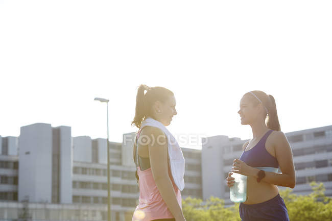 Two young female runners chatting on urban rooftop — Stock Photo