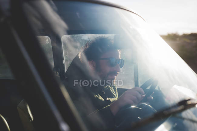 Homme portant des lunettes de soleil voiture de conduite à la lumière du soleil — Photo de stock