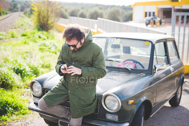 Metà uomo adulto sms su smartphone accanto al binario ferroviario — Foto stock