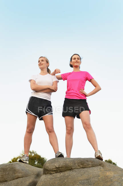 Retrato de dos orgullosas corredoras en la cima de la formación rocosa - foto de stock