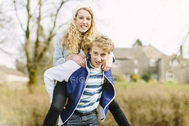 Adolescent garçon donnant copine piggyback — Photo de stock