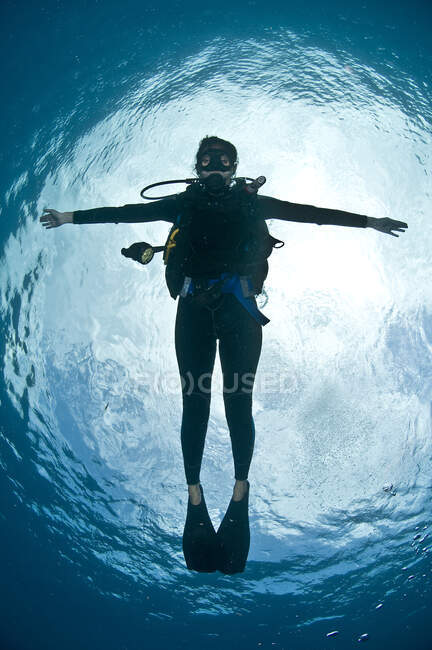 Vue de face pleine longueur des bras de plongée sous-marine ouverts flottant près de la surface de l'eau en regardant la caméra, atoll Chinchorro, Quintana Roo, Mexique — Photo de stock