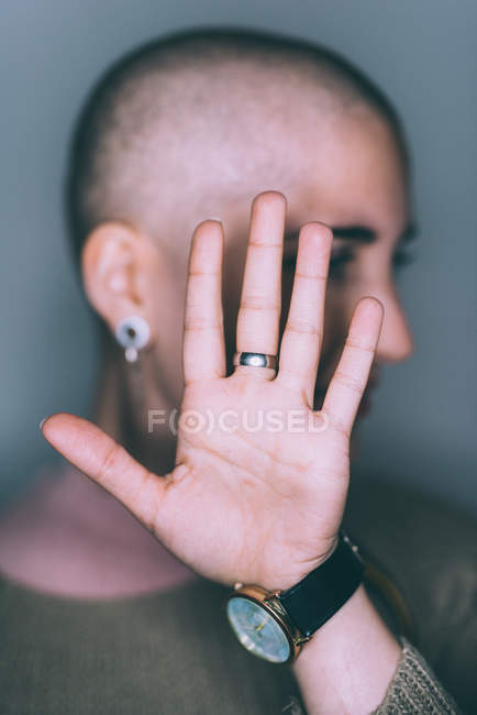 Портрет молодой женщины с бритой головой и рукой перед лицом — стоковое фото
