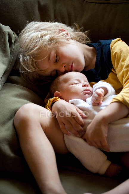 Young boy holding baby brother — Stock Photo