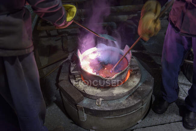 Workers stirring molten aluminium alloy in precision casting factory — Stock Photo