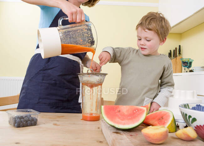 Menino e mãe fazendo smoothies de frutas — Fotografia de Stock