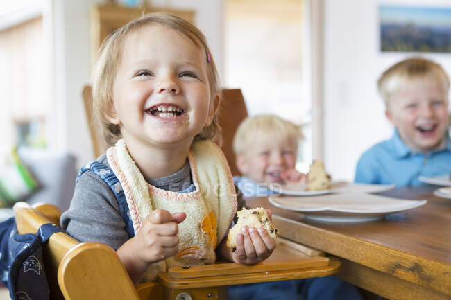 Trois jeunes enfants mangeant du gâteau à table de thé — Photo de stock