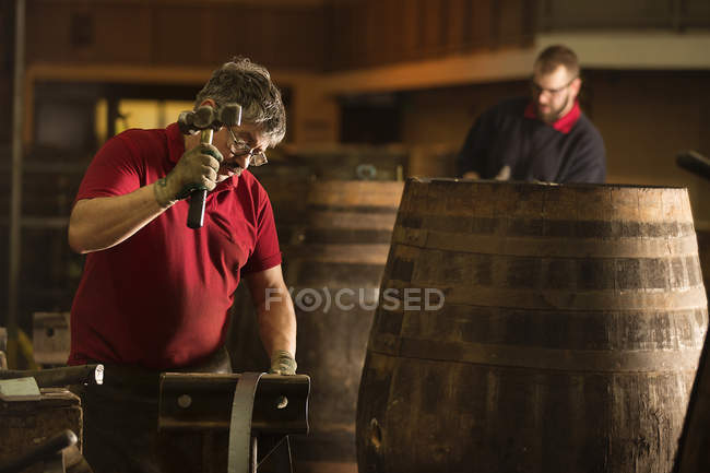 Küfermännchen mit Hammer in Küferei mit Whisky-Fässern — Stockfoto