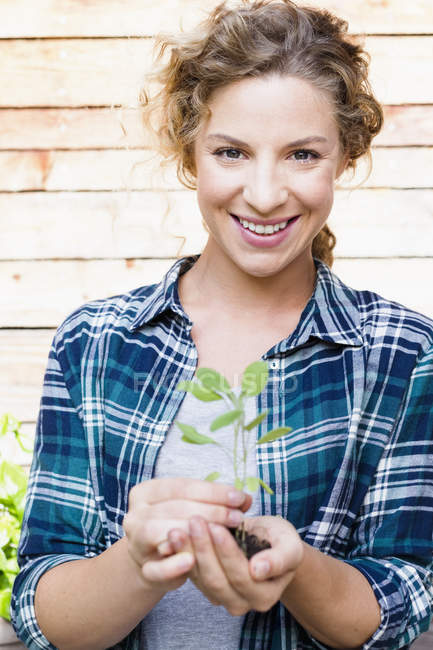 Young woman holding seedling, portrait — Stock Photo