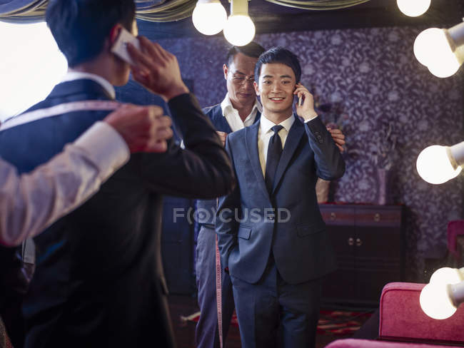 Young man trying on suit in traditional tailors shop — Stock Photo