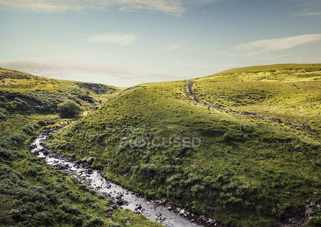 Río que fluye a través de verdes colinas - foto de stock